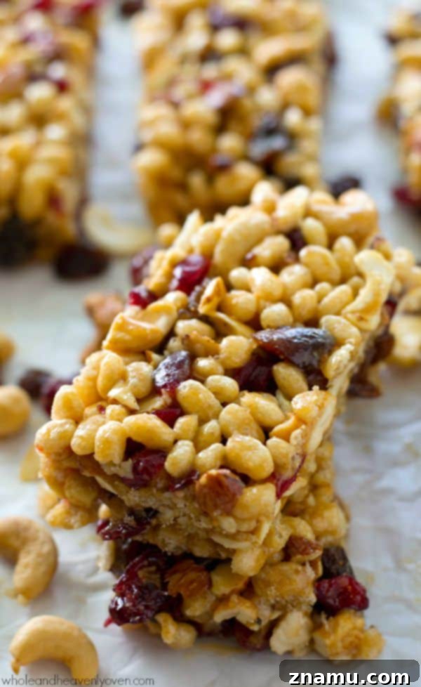 No-Bake Fruit and Nut Power Bars 6 Hand holding a square piece of no-bake fruit and nut bar, showcasing its dense, chewy texture and visible wholesome ingredients.