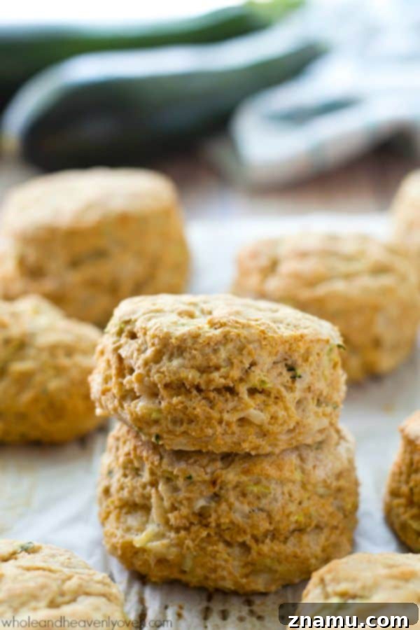 Savory Zucchini Parmesan Buttermilk Biscuits 7 Hand reaching for a freshly baked zucchini Parmesan buttermilk biscuit.