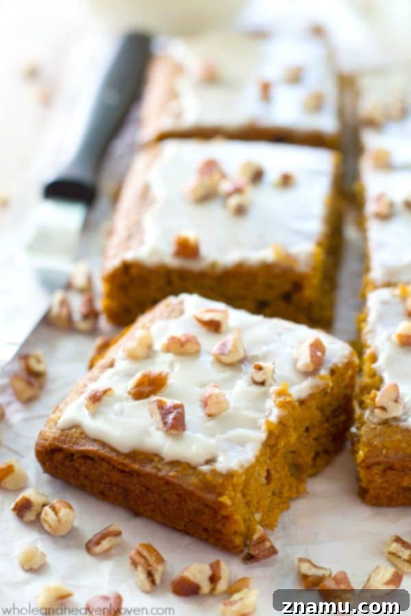 Velvet Pumpkin Spice Glaze Bars 2 Delicious glazed pumpkin spice cake bars topped with chopped pecans, ready to be served on a white platter.