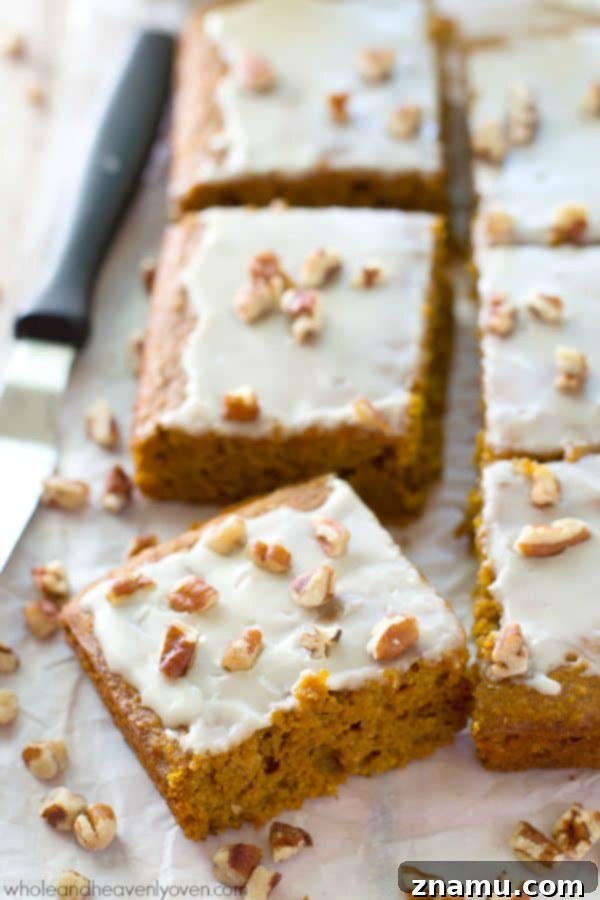 Velvet Pumpkin Spice Glaze Bars 4 Three glazed pumpkin cake bars artfully arranged on a dark plate, showcasing their soft texture and sweet topping.