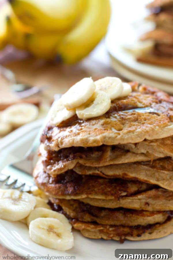 Bakery Banana Swirl Pancakes 2 A towering stack of golden brown banana bread cinnamon roll pancakes, drizzled generously with maple syrup, beckoning for a delightful breakfast.