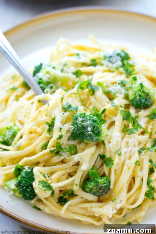 Broccoli Garlic Fettuccine Alfredo in 20 Minutes 3 Close-up of creamy fettuccine alfredo with broccoli and garlic, garnished with parsley.