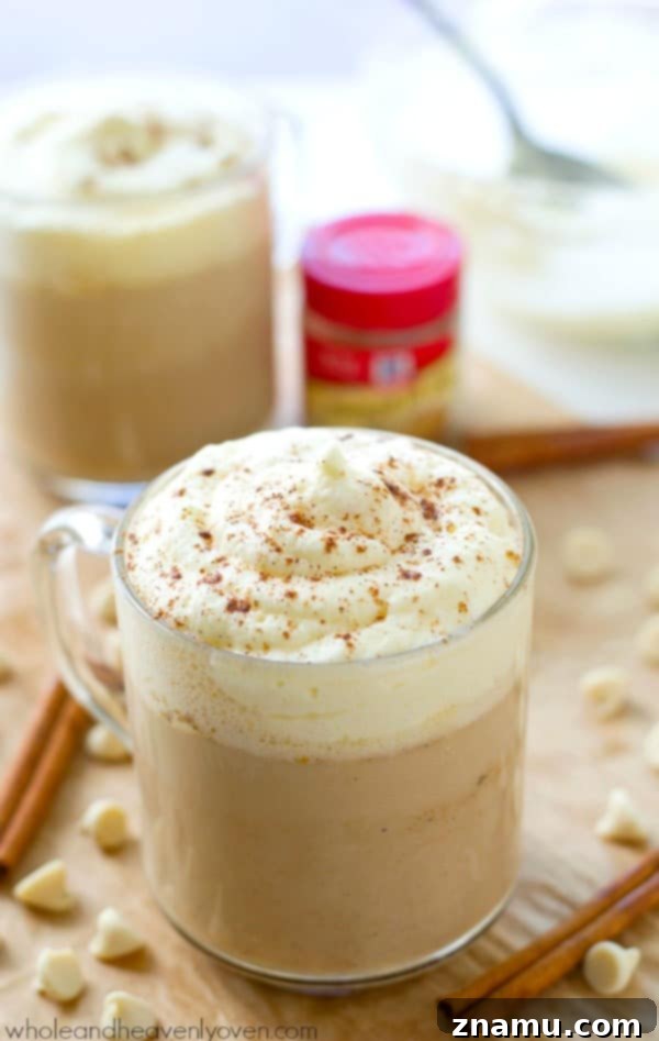 Pumpkin Spice White Chocolate Mocha 2 A steaming mug of White Chocolate Pumpkin Spice Mocha, topped with luscious whipped cream and a sprinkle of pumpkin spice, promising cozy comfort.