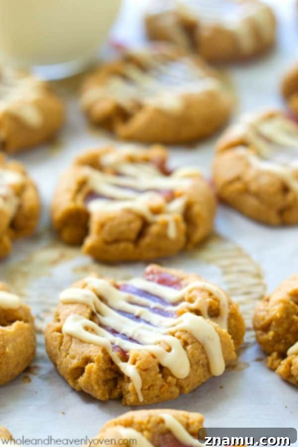 An array of white chocolate peanut butter and jelly thumbprint cookies on a wire cooling rack, ready to be served.