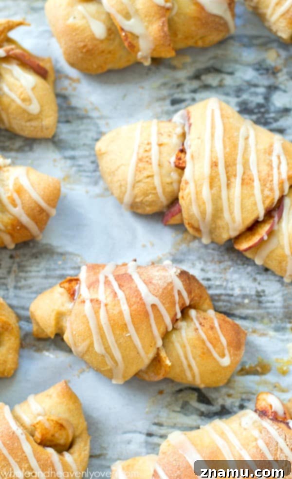 Sweet Glazed Apple Pie Crescents 6 Freshly baked glazed apple pie crescent rolls on a baking sheet