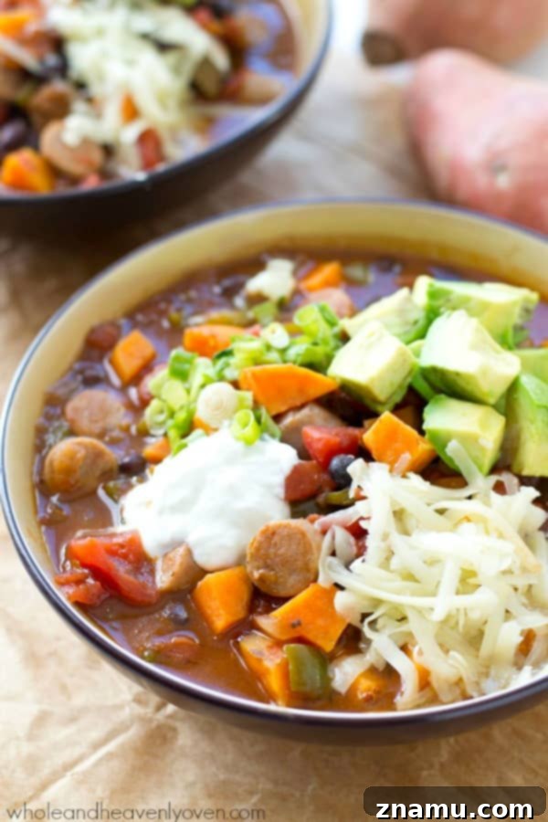 Hearty Slow Cooker Sweet Potato Sausage Chili 2 Close-up of a hearty bowl of Crockpot Sweet Potato Sausage Chili, garnished with fresh cilantro and sour cream.