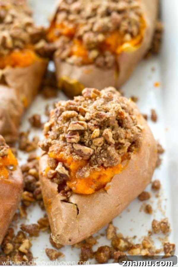 Creamy Twice-Baked Sweet Potatoes with Crunchy Pecan Streusel 4 Hand scooping creamy sweet potato filling from a roasted sweet potato skin, preparing for the second bake.