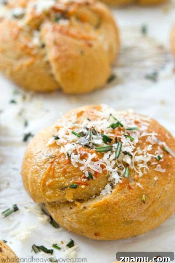 Garlic Rosemary Parmesan Knots 6 Hand reaching for a Parmesan Garlic Rosemary Knot from a baking sheet, highlighting the soft, irresistible texture.