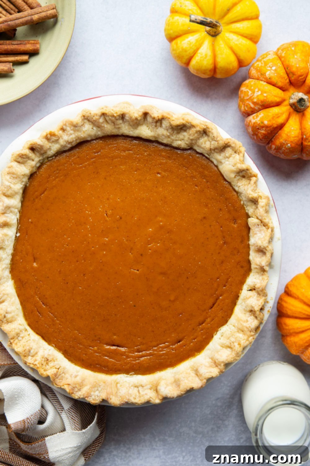 The Ultimate Pumpkin Pie 3 A slice of classic pumpkin pie topped with generous homemade whipped cream, perfect for Thanksgiving.