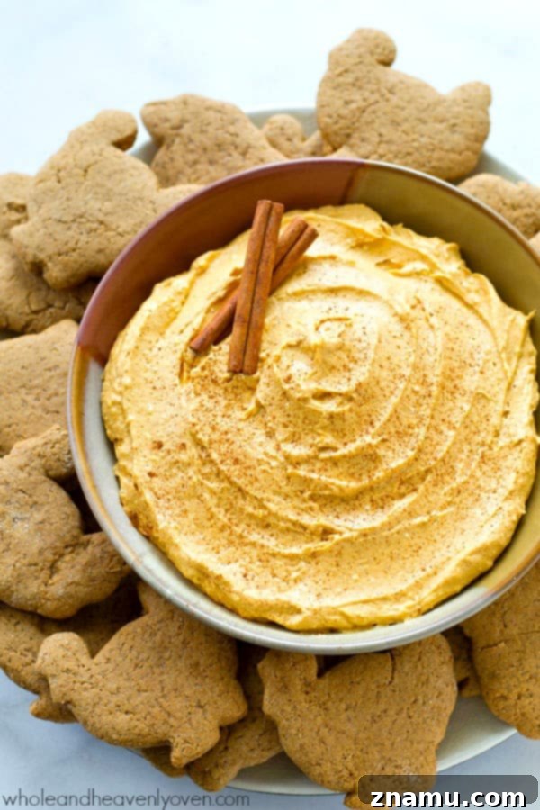 Spiced Pumpkin Cheesecake Dip with Zesty Gingersnap Dippers 5 A bowl of creamy pumpkin cheesecake dip with a spoonful taken, showcasing its smooth texture. A perfect snack for any time. @WholeHeavenly