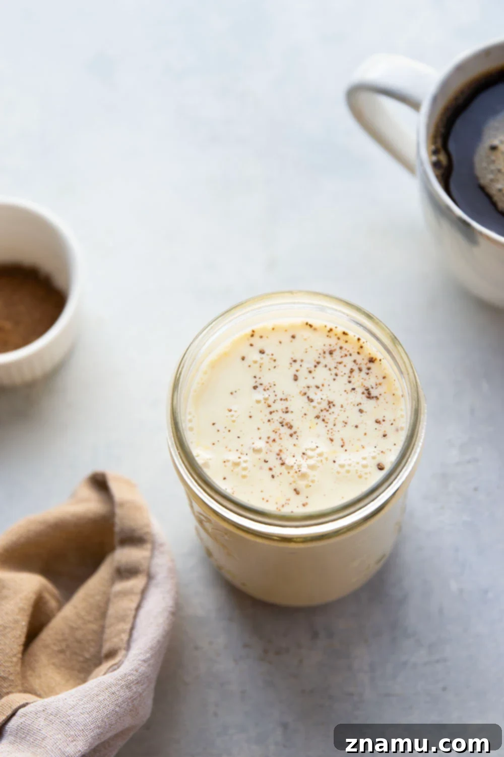 Spiced Eggnog Coffee Delight 4 Freshly made eggnog coffee creamer in a glass jar, garnished with nutmeg.