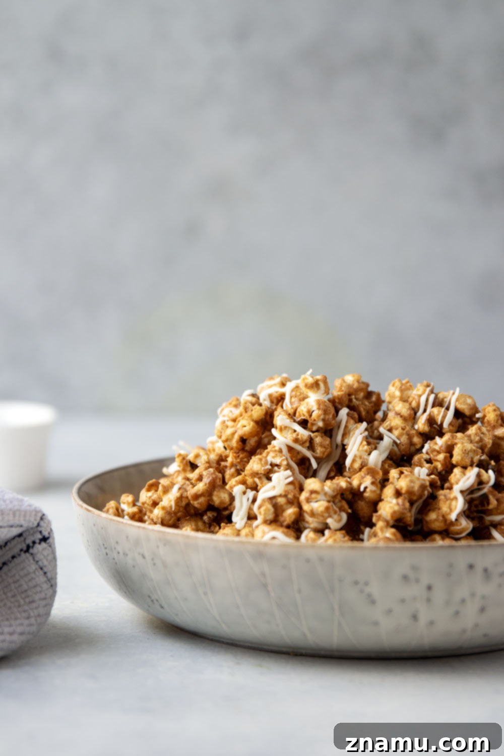 Gingerbread Caramel White Chocolate Crunch 6 A close-up of a large piece of gingerbread caramel popcorn, highlighting the crisp texture and sweet coating.