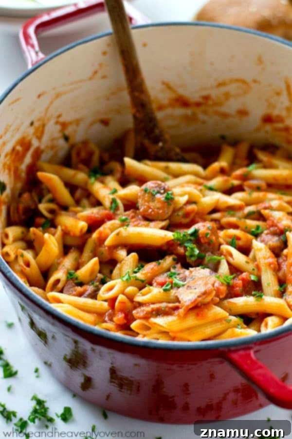 Effortless 30-Minute Penne Vodka with Sausage 5 A large serving spoon scooping penne sausage alla vodka from a dutch oven, highlighting the creamy texture.