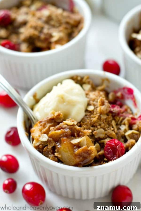 Mini Pear Cranberry Crisps for One 6 A freshly baked mini pear cranberry crisp topped with a generous dollop of whipped cream, ready to eat.