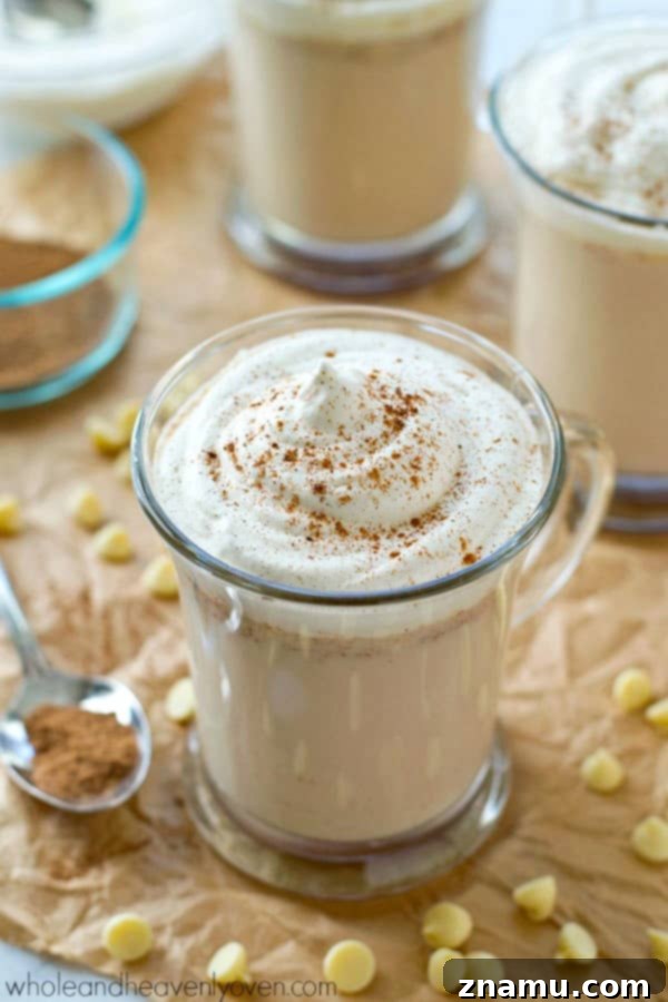 Delicious chai white hot chocolate topped with whipped cream and spices, ready to be enjoyed as a festive slow cooker beverage.