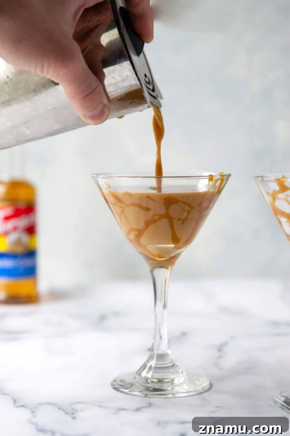 The Salted Caramel Espresso Martini 5 A martini glass filled with a Salted Caramel Espresso Martini, decorated with caramel drizzles and three coffee beans on top.