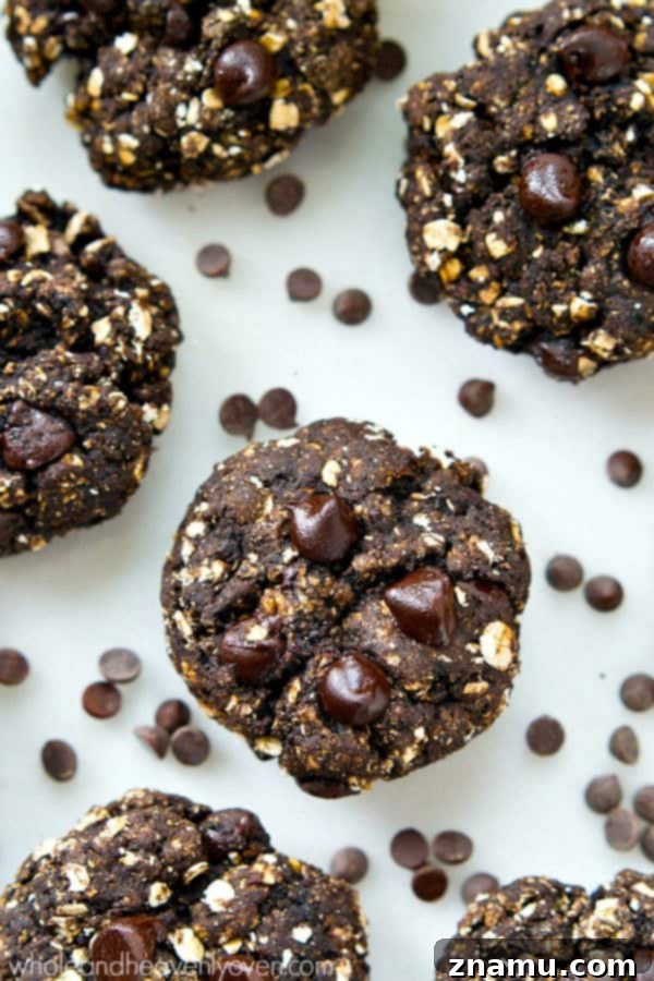 A plate of freshly baked healthy double chocolate breakfast cookies, with a few stacked enticingly on a wooden board.