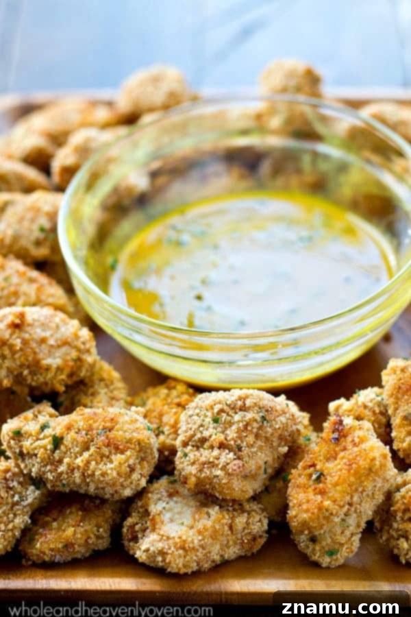 Golden Crunch Baked Chicken Bites with Zesty Honey Mustard 3 Close-up of golden brown extra-crispy baked chicken nuggets on a plate, ready to be dipped.