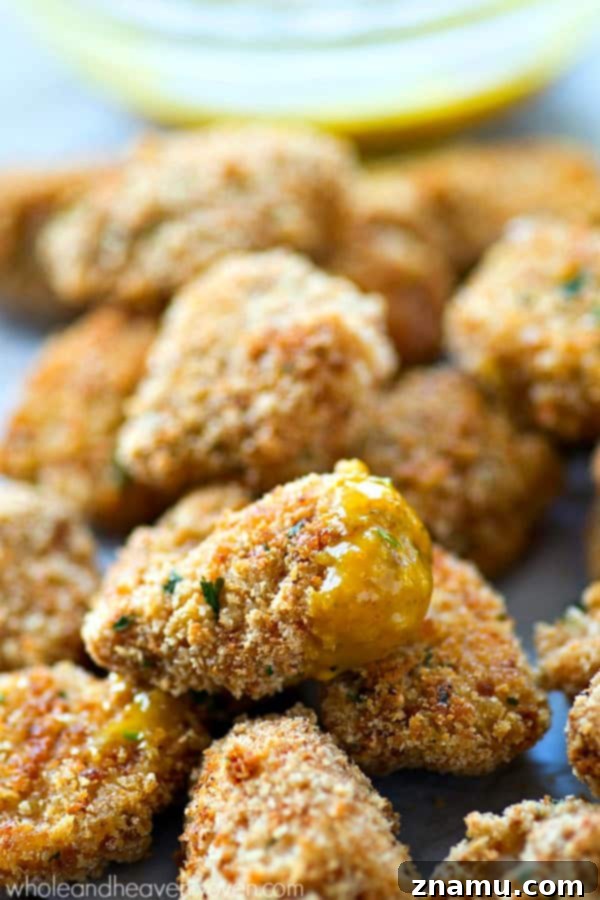 Golden Crunch Baked Chicken Bites with Zesty Honey Mustard 4 Hands dipping an extra-crispy oven-baked chicken nugget into a bowl of tangy honey mustard dip.