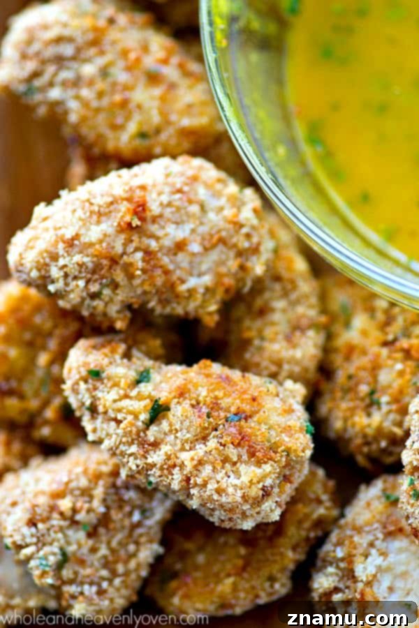 Golden Crunch Baked Chicken Bites with Zesty Honey Mustard 5 A bowl of homemade tangy honey mustard dip with a spoon, ready for dipping crispy chicken nuggets.