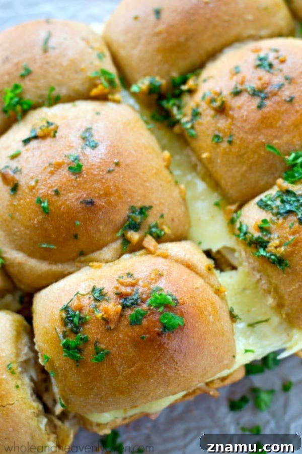 Ultimate Garlic Butter Monte Cristo Pull-Apart Sliders 7 Hot, gooey Monte Cristo Sliders being pulled apart, showcasing melted cheese.
