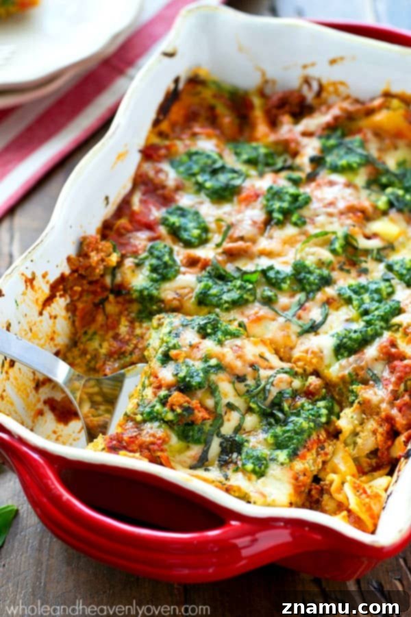 Triple Cheese Pesto Turkey Bake 5 A serving of warm turkey pesto lasagna on a white plate, garnished with fresh basil leaves