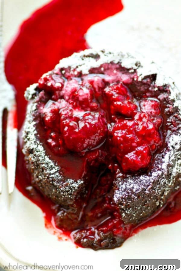 Molten Chocolate Raspberry Dream 3 Close-up of a chocolate lava cake revealing its warm, molten chocolate center as a spoon scoops into it.
