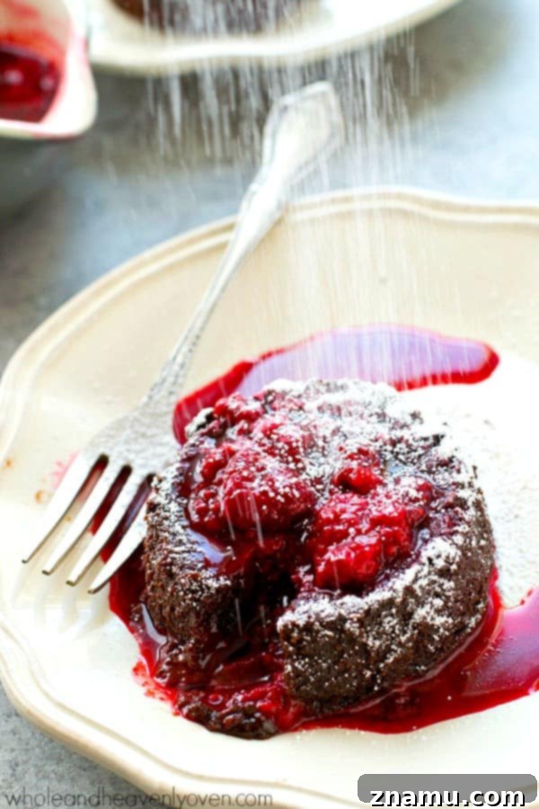 Molten Chocolate Raspberry Dream 6 A freshly baked chocolate lava cake adorned with powdered sugar and a generous drizzle of homemade raspberry sauce, ready to be served.