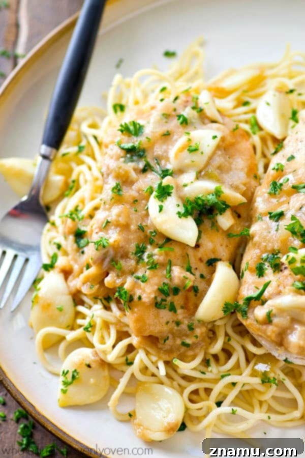 Close-up of tender crockpot chicken breasts coated in a creamy garlic sauce, ready to be served over pasta or rice.