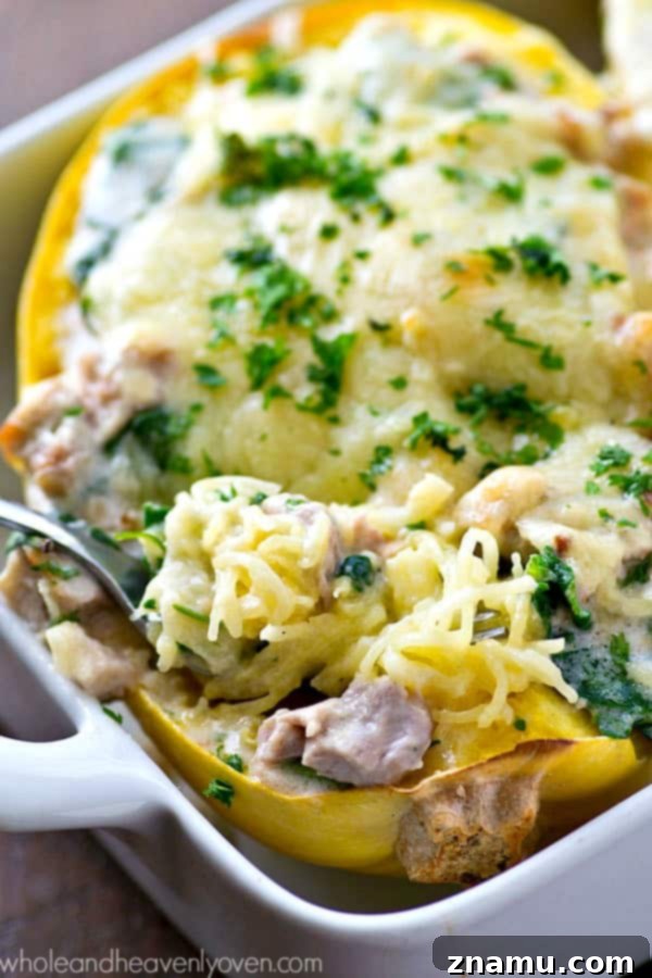 Creamy Spinach Chicken Alfredo Spaghetti Squash Boats 6 A close-up of a single Chicken Alfredo Spaghetti Squash Boat with a fork, showing the creamy filling and melted cheese