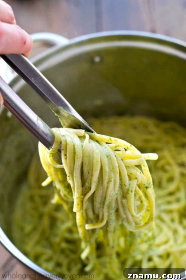 Guilt-Free Creamy Spinach Fettuccine Alfredo 3 Close-up of vibrant green spinach alfredo sauce coating fettuccine pasta, highlighting the creamy texture and fresh ingredients.