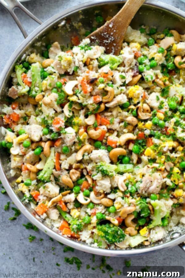 Rainbow Chicken Cauliflower Fried Rice 4 Overhead shot of freshly prepared Chicken Rainbow Veggie Cauliflower Fried Rice with cashews and green herbs as garnish.