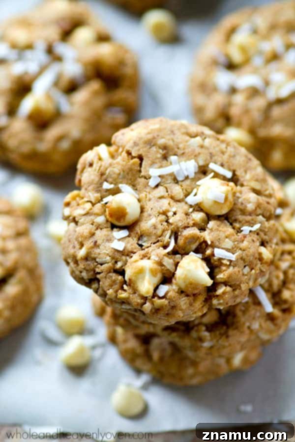 Chewy White Chocolate Coconut Oat Bliss 4 A stack of white chocolate coconut oatmeal cookies on a cooling rack, showcasing their perfect golden-brown edges.