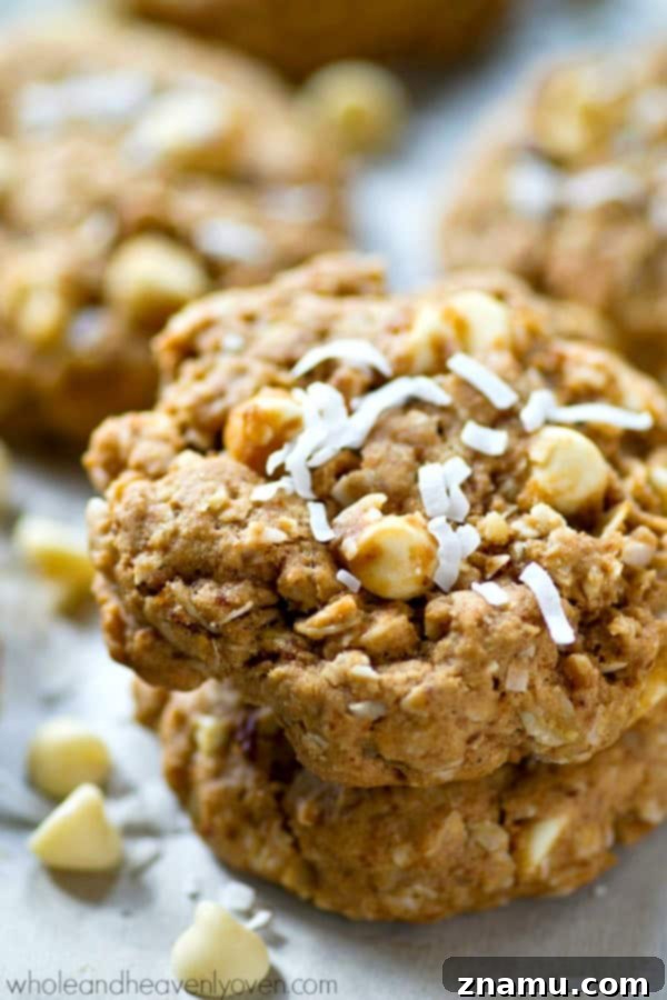 Chewy White Chocolate Coconut Oat Bliss 5 A hand reaching for a freshly baked chewy white chocolate coconut oatmeal cookie, emphasizing its homemade appeal.