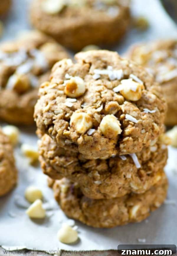 Chewy White Chocolate Coconut Oat Bliss 6 A close-up shot of several chewy white chocolate coconut oatmeal cookies cooling, showcasing their delicious golden color.