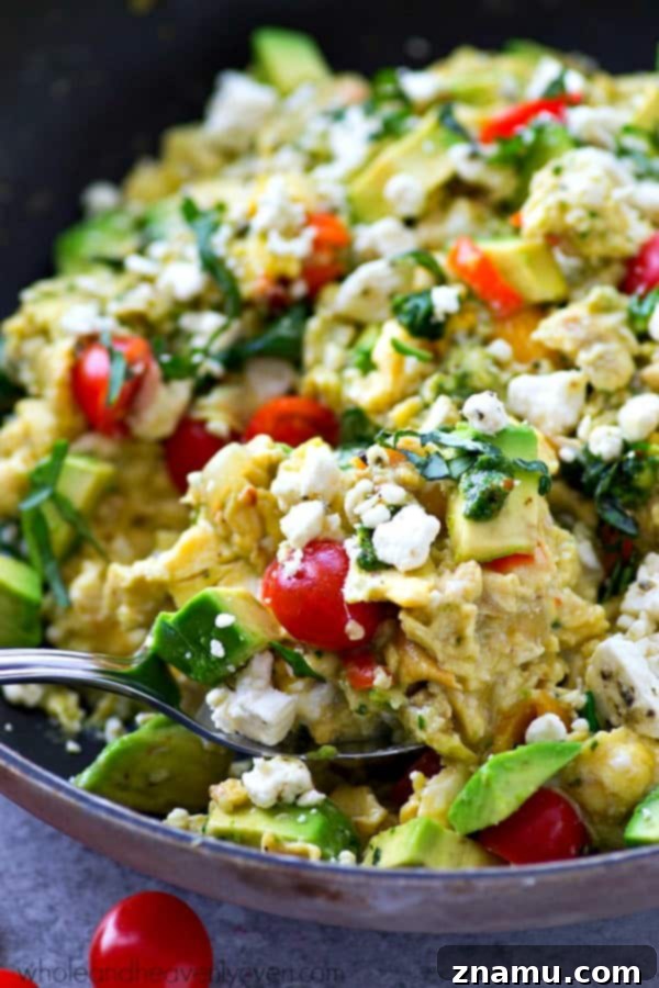 Pesto Garden Scramble 3 Close-up of fluffy scrambled eggs brimming with diced bell peppers, onions, spinach, and green pesto swirls