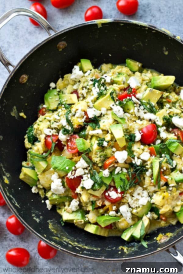 Pesto Garden Scramble 4 Overhead view of a skillet of scrambled eggs mixed with various vegetables and pesto, ready to serve