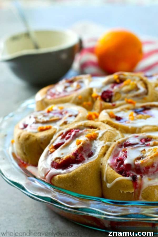 Zesty Orange Raspberry Swirl Buns 3 Close-up of fluffy Orange Raspberry Swirl Cinnamon Rolls, showing their vibrant pink filling.