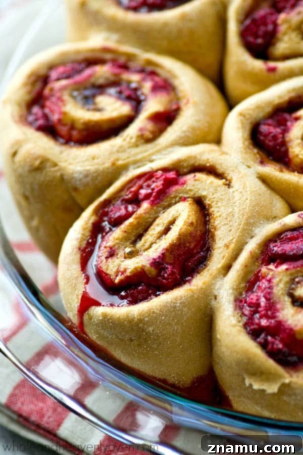 Zesty Orange Raspberry Swirl Buns 4 Freshly baked Orange Raspberry Swirl Cinnamon Rolls cooling on a rack, before glazing.