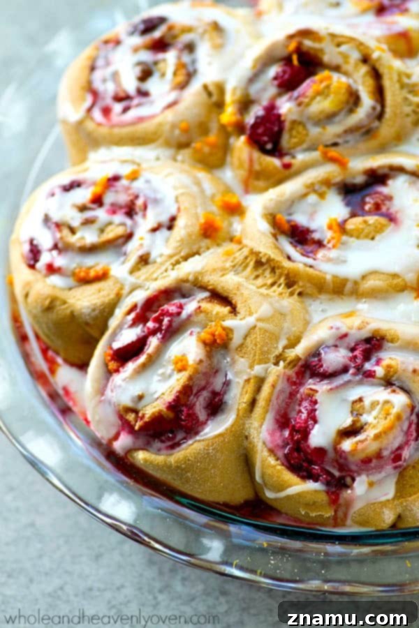 Zesty Orange Raspberry Swirl Buns 7 Drizzled glaze cascading over warm Orange Raspberry Swirl Cinnamon Rolls.