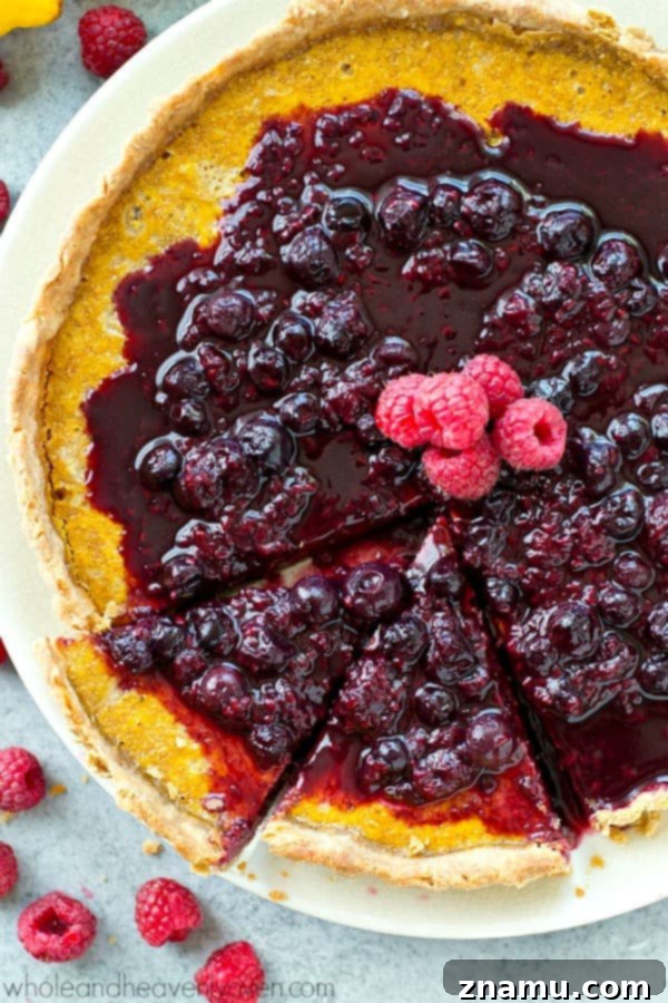 A slice of luscious lemon tart with mixed berry citrus sauce, presented elegantly.