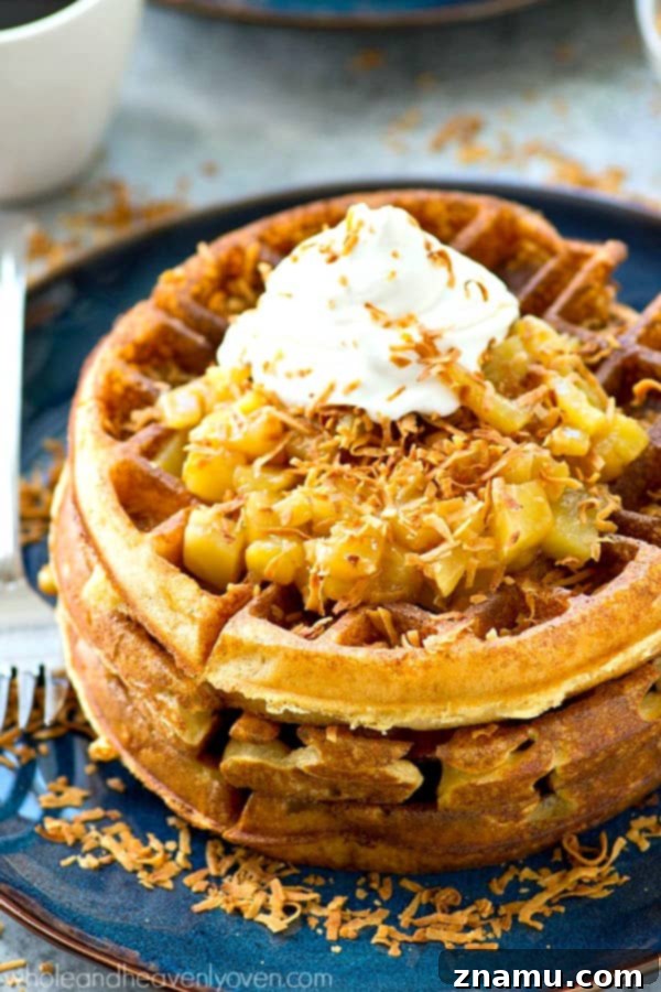 Tropical Overnight Waffle Bliss 6 A hand holding a fork, about to dig into a plate of crispy yeast waffles with pina colada topping.