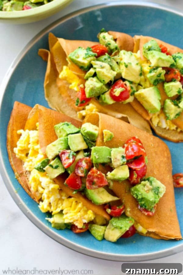 Gourmet Savory Crepes: Scrambled Eggs & Zesty Avocado Pico 7 Overhead shot of two savory crepes on a rustic plate, beautifully folded and topped with avocado pico de gallo and a sprig of fresh cilantro, ready to be enjoyed.
