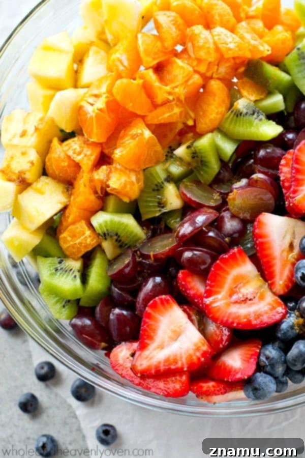 Vibrant Fruit Medley with Zesty Ginger-Lime Drizzle 7 A close-up of the rainbow fruit salad, showcasing juicy strawberries, firm blueberries, succulent pineapple, and bright green kiwi pieces, all lightly coated in the ginger-lime dressing.
