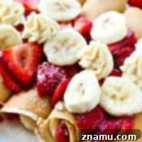 A single Strawberry Banana Cheesecake Crepe, garnished with fresh strawberries, ready to be enjoyed.
