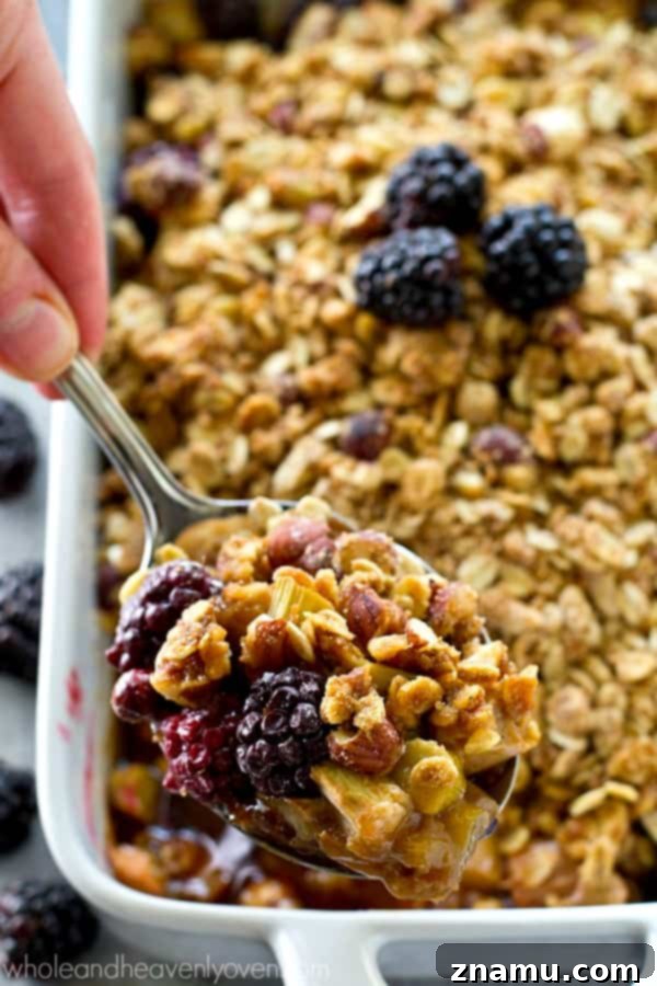 A close-up of the crumbly almond streusel topping, featuring oats, sliced almonds, and a golden hue, sprinkled over the fruit filling.