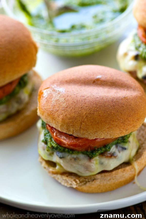 Grilled Pesto Turkey Burgers with Melted Mozzarella and Smoky Tomatoes 4 Fresh basil pesto being spooned onto a turkey burger patty, ready for serving