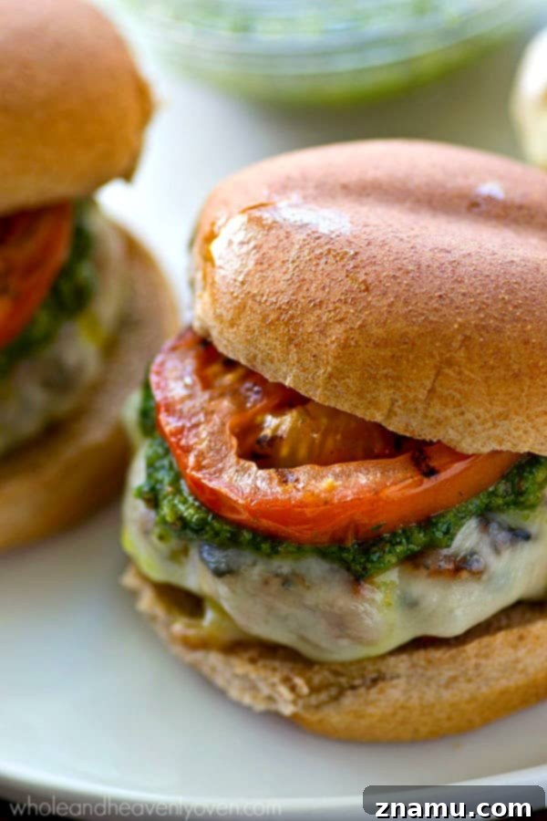 Grilled Pesto Turkey Burgers with Melted Mozzarella and Smoky Tomatoes 5 Close-up shot of a turkey burger with pesto, mozzarella, and grilled tomatoes, ready to eat