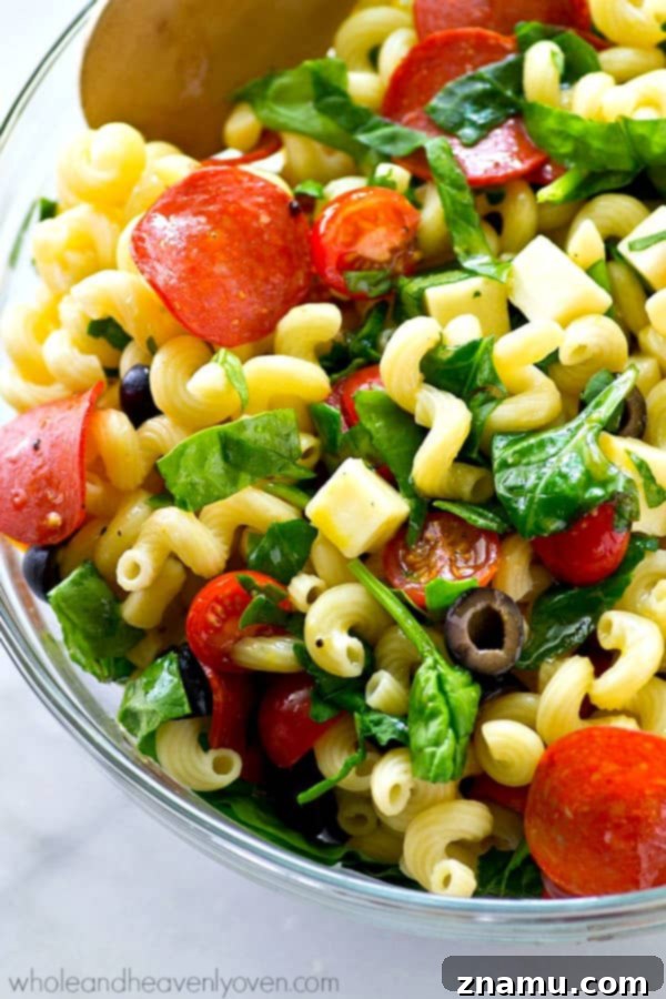A bowl of fresh and vibrant Italian Pizza Pasta Salad on a picnic table