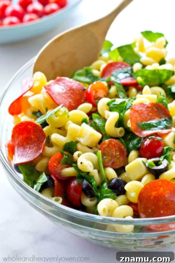 Hand reaching for a serving of the irresistible Italian Pizza Pasta Salad
